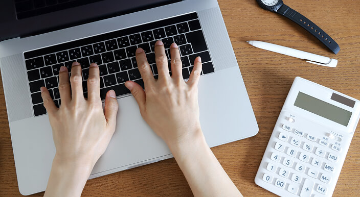 PCと電卓を使って業務を行う人